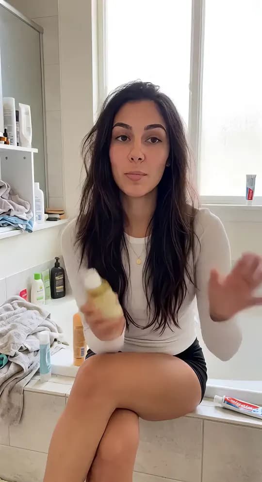 Talking creator reviewing a hair oil in her bathroom